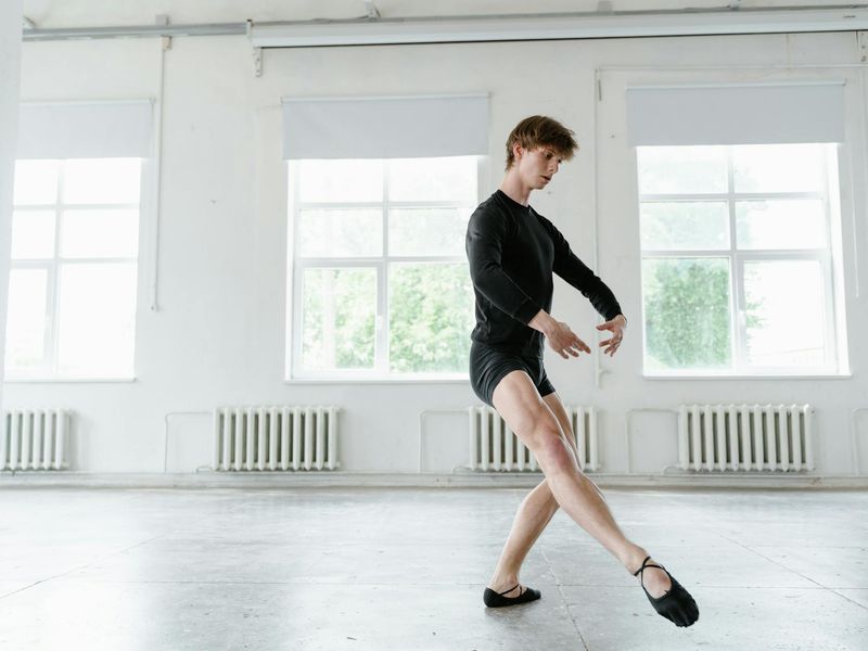 Man performing a controlled bodyweight exercise in a minimalist room.